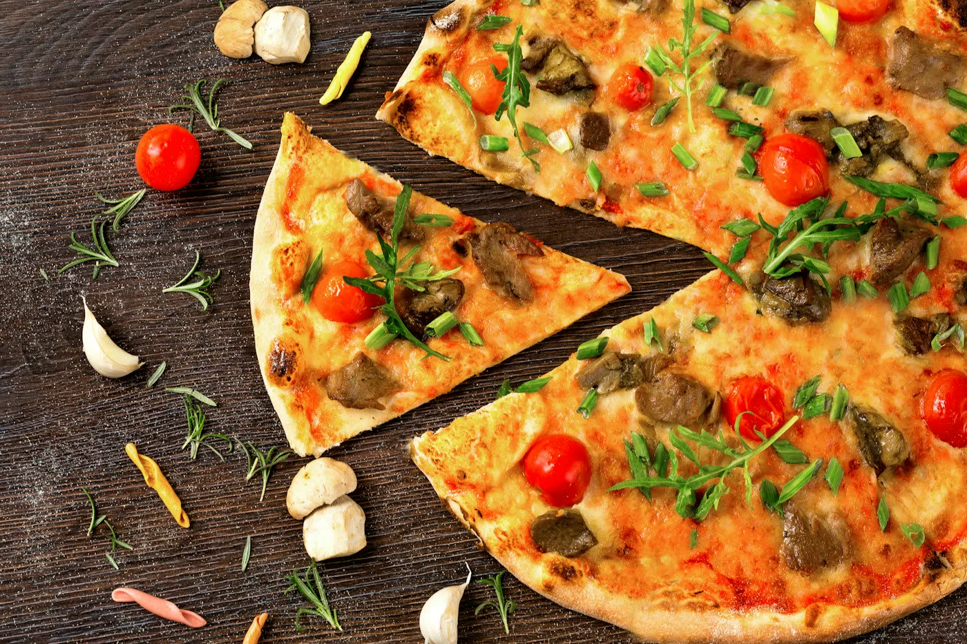 Pizza mit Champignons und Tomaten auf einem Holzbrett
